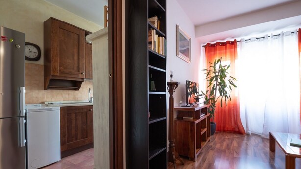 A kitchen with wooden cabinets, a refrigerator, and a clock on the wall.