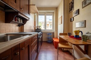 A kitchen with wooden cabinets, a sink, and a window. - Rialto Apartment Vatican Museums (Rome)