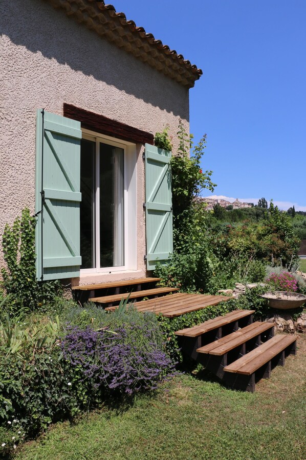 A house with a wooden deck, a window with green shutters, and a garden with various plants and flowers. - 4 Bed Idyllic Fayence Retreat Private Pool Great Views (Fayence)
