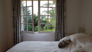 A bedroom with a large window, a bed with a white textured bedspread, and a nightstand with a lamp. - 4 Bed Idyllic Fayence Retreat Private Pool Great Views (Fayence)