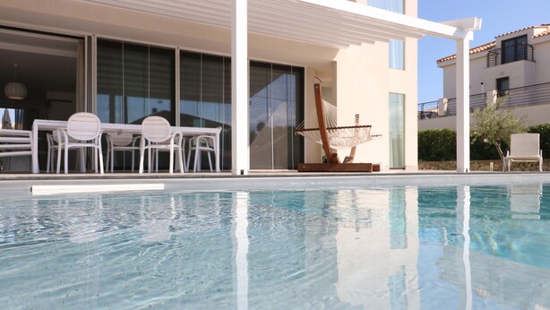 A swimming pool with a white outdoor seating area, including chairs and a table, and a hammock. - Deluxe Villa with private pool and jacuzzi 2km from Ortigia, Sicily (Siracusa)