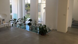 A modern interior with large windows, a glass coffee table, and potted plants. - Deluxe Villa with private pool and jacuzzi 2km from Ortigia, Sicily (Siracusa)
