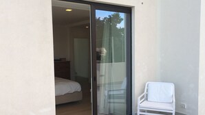 A room with a bed, a chair, and a sliding glass door leading to an outdoor area. - Deluxe Villa with private pool and jacuzzi 2km from Ortigia, Sicily (Siracusa)