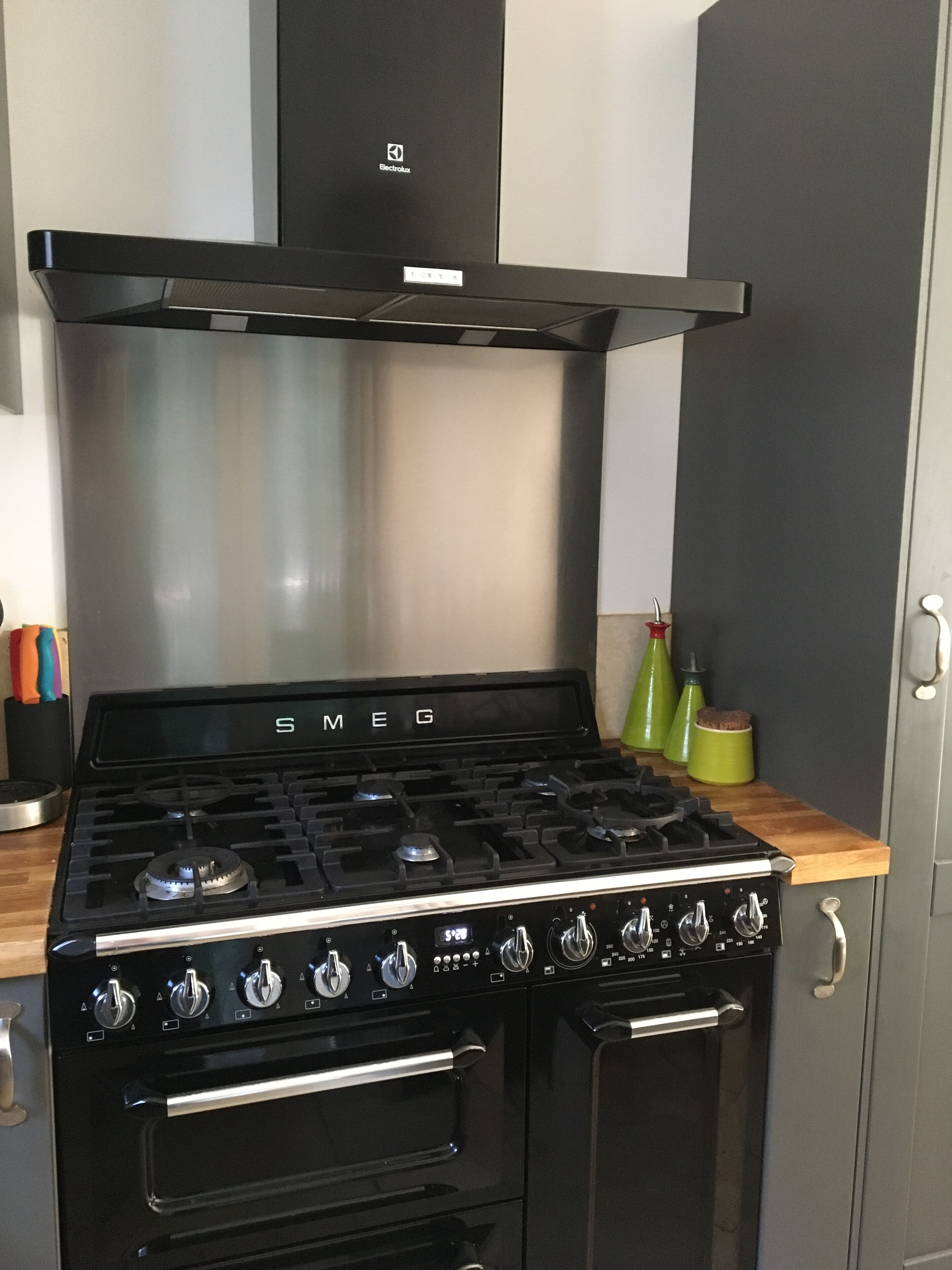 Une cuisinière Electrolux noire, dotée de quatre brûleurs et d’une hotte en acier inoxydable.