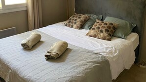 A neatly made bed with two towels, a bedside lamp, and patterned pillows. - 5 bedroom VILLA with pool on a hillside near AIX  (Mimet)