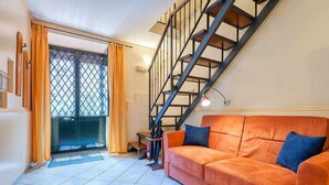 A living room with a staircase, a sofa, and a door with curtains. - Opera House Suite with Balcony (Catania)