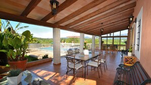 Un patio al aire libre con techo de madera, piscina y vistas a las montañas.