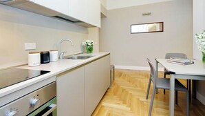 A modern kitchen with a built-in stove, a sink, and a dining area with a table and chairs. - COLOSSEUM ELEGANT APARTMENT FOR 4 - NEAR METRO (Roma)
