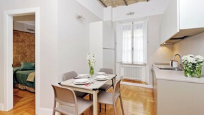 A compact living space with a dining area, kitchenette, and a bedroom with a wooden headboard. - COLOSSEUM ELEGANT APARTMENT FOR 4 - NEAR METRO (Roma)
