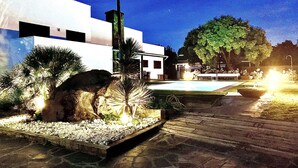 A modern building with a pool, surrounded by landscaped areas and a stone pathway.