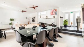 A modern dining area with a glass table, black chairs, and ceiling fans.