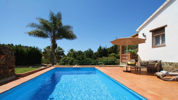 A rectangular swimming pool with clear blue water, surrounded by a tiled deck and a stone wall. - 1076 Cortijo de la Musica (Frigiliana)