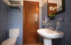 A bathroom with a wooden door, a toilet, a sink with a mirror, and a potted orchid. - 1076 Cortijo de la Musica (Frigiliana)