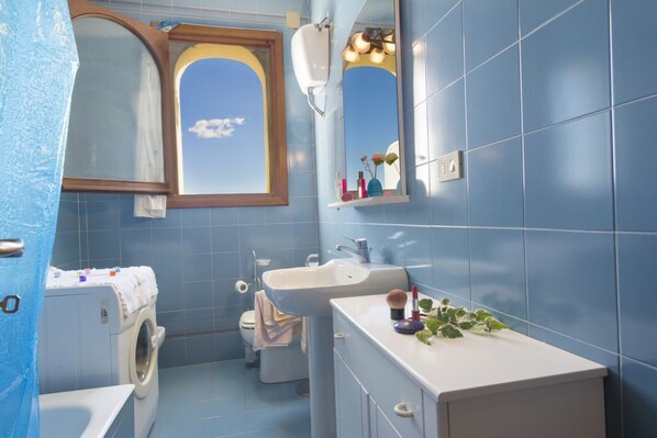 Un baño con lavadora, lavabo y espejo.