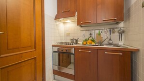 A compact kitchen with wooden cabinets, a stainless steel stove, and a sink.