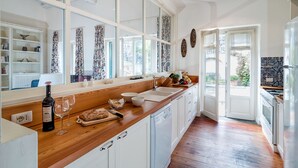 Een moderne keuken met houten aanrechtbladen, witte kastjes en een groot raam.