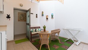 A small, enclosed patio area with a table and chairs, a drying rack, and a door leading to another room.