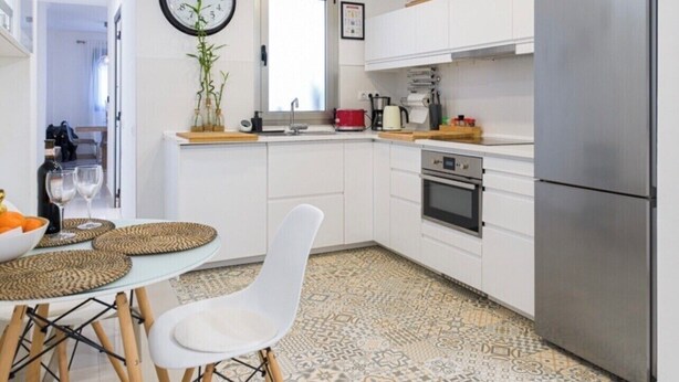 A modern kitchen with white cabinets, a stainless steel refrigerator, and a patterned tile floor.