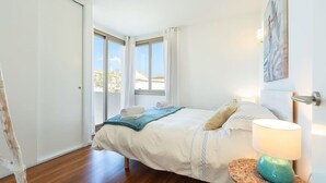 A bedroom with a bed, a nightstand, a lamp, and a view through a window.