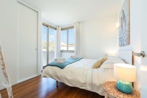A bedroom with a bed, a nightstand, a lamp, and a view through a window. - Modern House With Panoramic Sea Views in Mallorca (Son Serra de Marina)