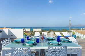 A dining table set with blue glassware and plates, overlooking a coastal view.