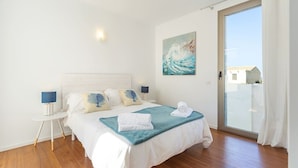 Une chambre à coucher avec un lit, des tables de chevet, un tableau et une vue à travers une porte vitrée.