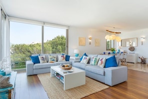 A modern living room with a grey sofa, a coffee table, and a dining area with a table and chairs.