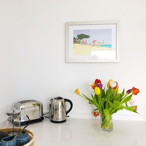 A kitchen counter with a toaster, a kettle, and a vase of tulips.