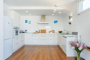 A modern kitchen with white cabinetry, a wooden countertop, and a built-in oven.