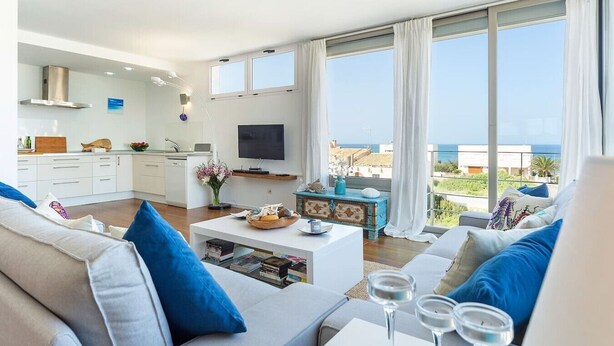 A modern living room with a sofa, coffee table, and a view of the sea.