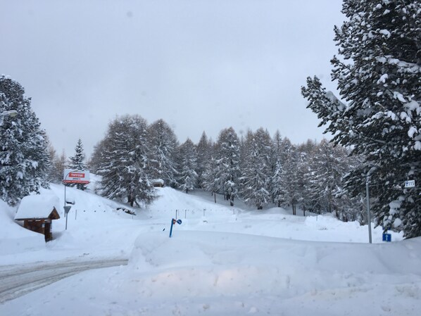 A snowy landscape with a road, a sign for 'Thyon 2000', and a blue directional sign.
