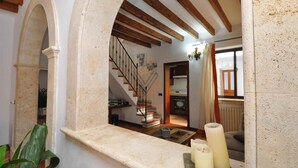 Ein Wohnzimmer mit Kamin aus Stein, einer Treppe und Blick zur Küche.
