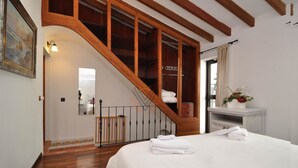 Ein Schlafzimmer mit einer Holztreppe, einem Bett mit weißen Leinen, einem kleinen Nachttisch und einem Spiegel.