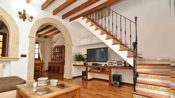 Ein geräumiges Wohnzimmer mit einer Holztreppe, einem Fernseher und einem Schrank.