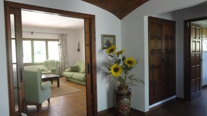 A living room with a green sofa, a wooden coffee table, and a vase with sunflowers. There is a door leading to another room. - Palenque CostaBravaSi - Pool, BBQ, garden, Golf (Santa Cristina d'Aro)