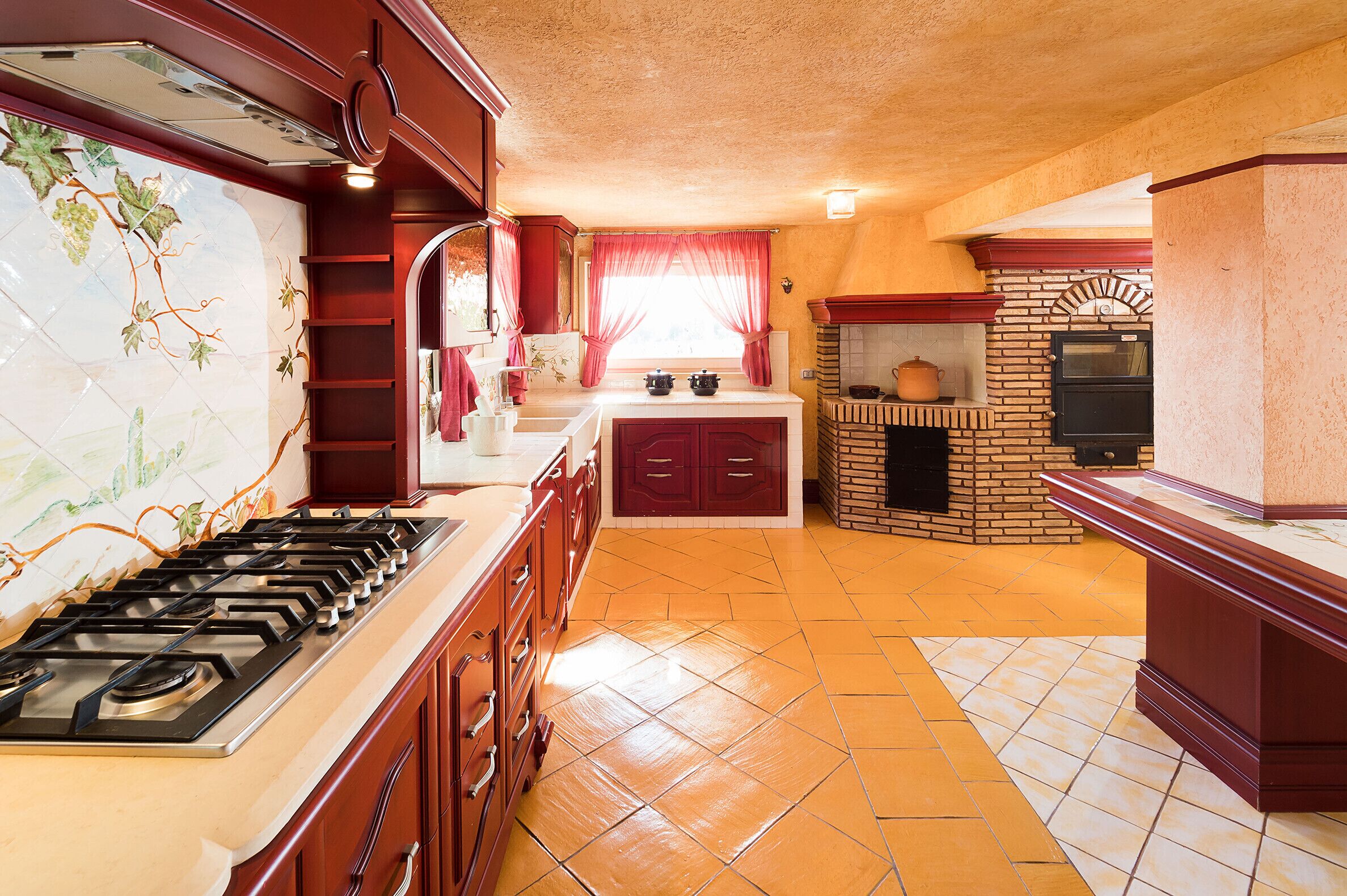 Une cuisine équipée d’une cuisinière à gaz, d’un four en briques et d’un dosseret carrelé.
