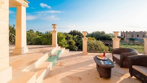 A terrace with wicker furniture, a pool, and a view of a historic building. - Luxury villa with heated pool and wellness area, 1,5 km away from sea, Donnalucata   - Villa Drago Spa (Scicli)