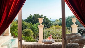 A balcony with wicker furniture, a wicker table with a bottle and glasses, and a view of lush greenery and a clear sky. - Luxury villa with heated pool and wellness area, 1,5 km away from sea, Donnalucata   - Villa Drago Spa (Scicli)