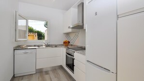 A modern kitchen with white cabinetry, a built-in oven, and a stainless steel sink. - Sa Marina 7A, villa direct on the beach (Alcudia - Puerto de Alcudia)
