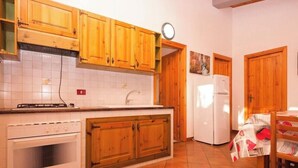 Una cocina con armarios de madera, una estufa blanca, un lavamanos y un refrigerador.