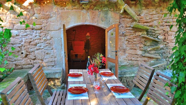 An outdoor dining area with a stone wall backdrop, wooden benches, and a table set for two with red plates and glasses. - Els Olivers 138 rustic finca with private swimming pool, air conditioning, terrace and barbecue (Alcúdia)