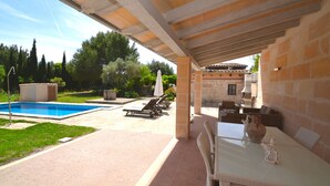 A covered outdoor area with a pool, lounge chairs, and a table with a vase. - Els Olivers 138 rustic finca with private swimming pool, air conditioning, terrace and barbecue (Alcúdia)