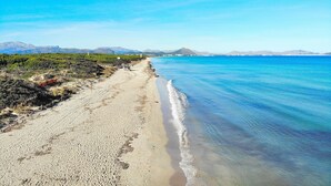 A beach with clear blue water, a sandy shore, and distant mountains. - Els Olivers 138 rustic finca with private swimming pool, air conditioning, terrace and barbecue (Alcúdia)