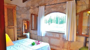 A bedroom with a bed, a window with curtains, a wooden cabinet, and a mirror. - Els Olivers 138 rustic finca with private swimming pool, air conditioning, terrace and barbecue (Alcúdia)