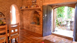 A rustic room with stone walls, a wooden door leading outside, and a tiled floor. - Els Olivers 138 rustic finca with private swimming pool, air conditioning, terrace and barbecue (Alcúdia)