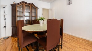 Ein Essbereich mit einem runden Tisch, braunen Polstermöbeln, einer weißen Tischdecke und einer Holzkabine mit Glastüren.