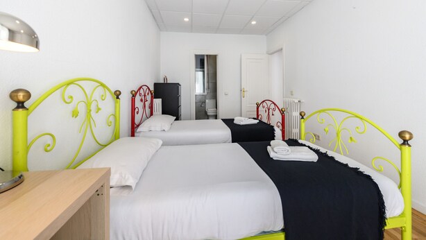 Ein Hotelzimmer mit zwei Einzelbetten, einem Holztisch und einer weißen Decke.