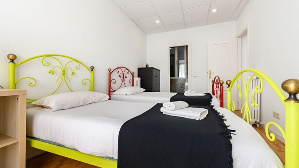 Habitación de hotel con dos camas, un armario, un radiador y una puerta.