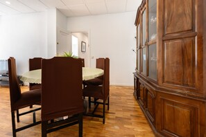 Un coin repas avec une table ronde, des chaises à revêtement marron et un buffet en bois doté de portes en verre.