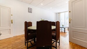 Comedor con una mesa redonda y seis sillas, paredes blancas y suelo de madera.